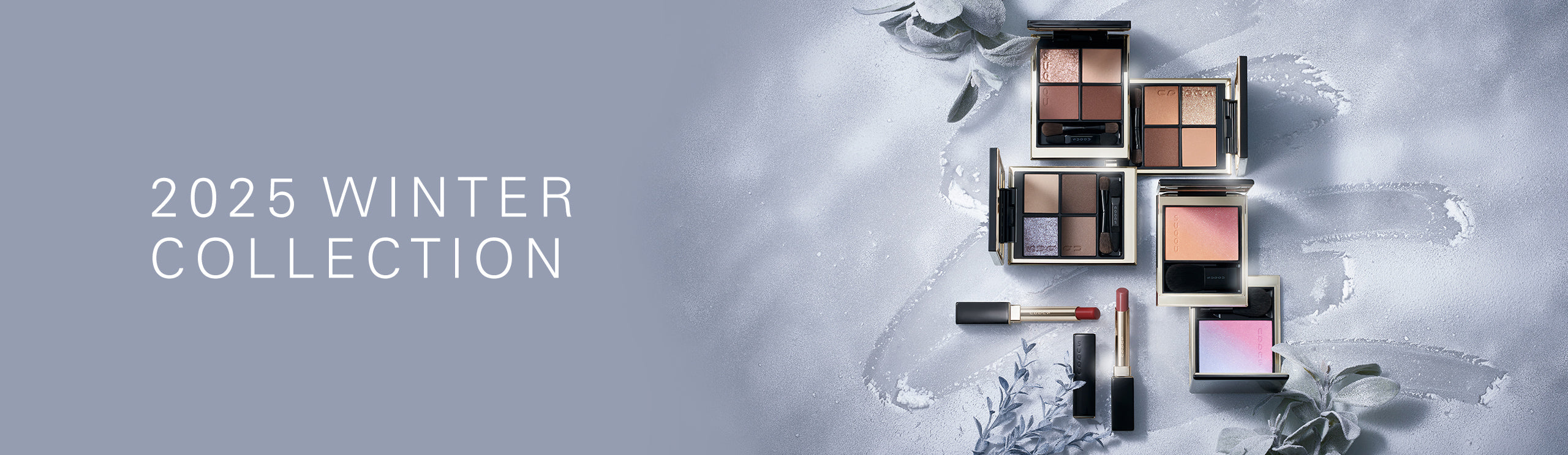 SUQQU Winter Colour Collection 2025 product group on frosted plant background. Multiple makeup palettes and lipsticks laid out together.