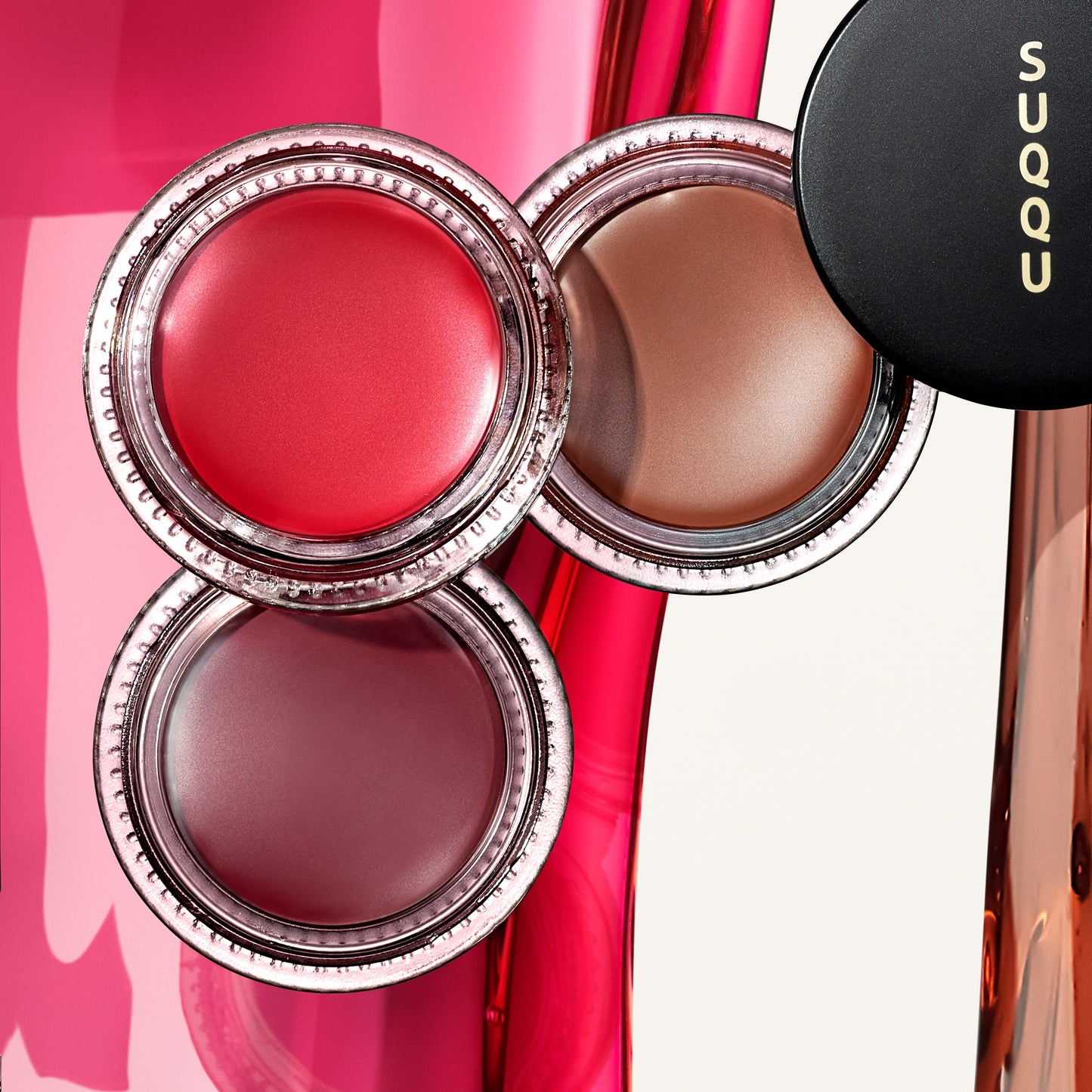 Three shades of SUQQU Cream Touch Blush and Lip product on colourful liquid background