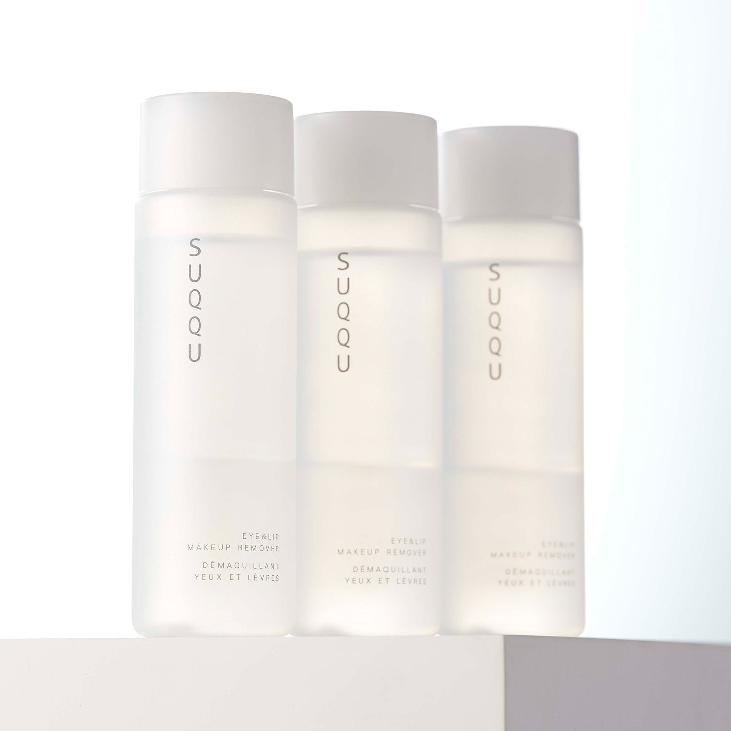 Three SUQQU Eye and Lip Makeup Remover cleansing products on stand.