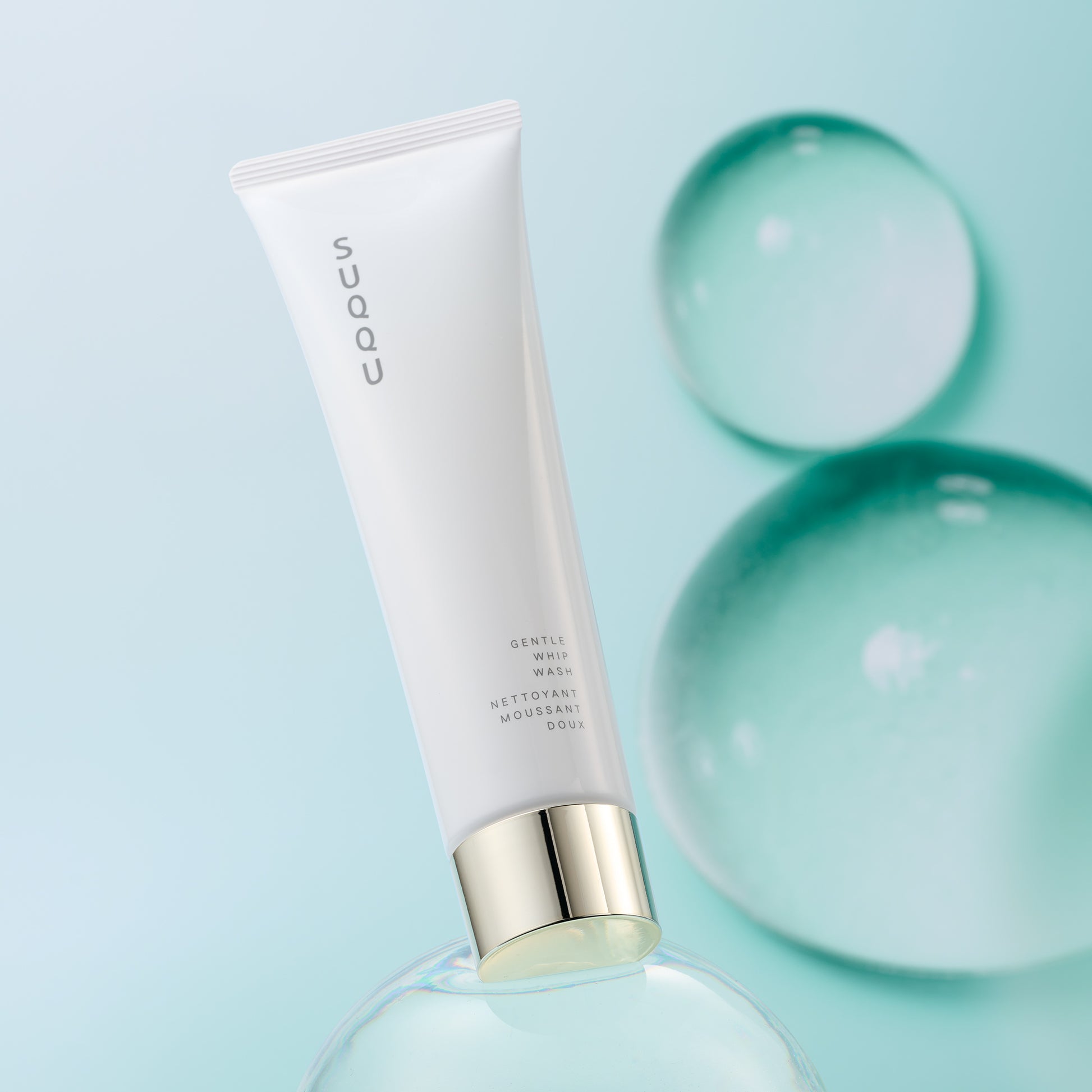 SUQQU Gentle Whip Wash foaming face cleansing skincare product tube on bubble background.