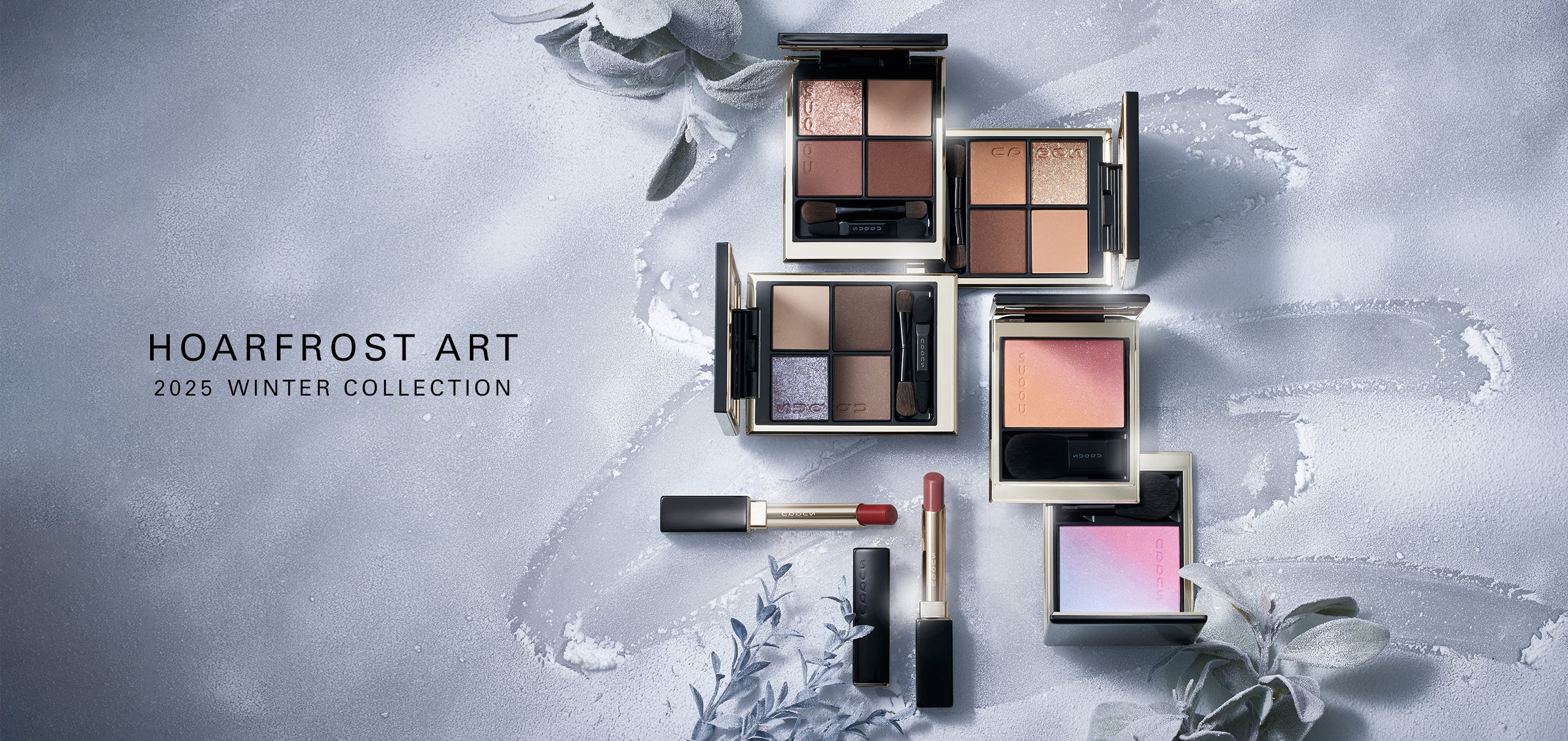 SUQQU Hoarfrost Art Winter Colour Collection 2025 product group on frosted plant background. Multiple makeup palettes and lipsticks laid out together.