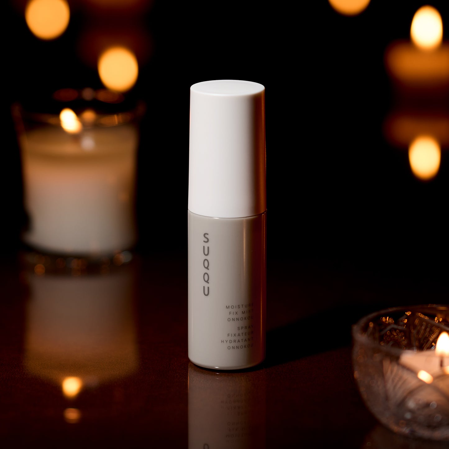 SUQQU Makeup Fix Mist Onnokou Japanese scented moisturising make up fix spray on dark background.