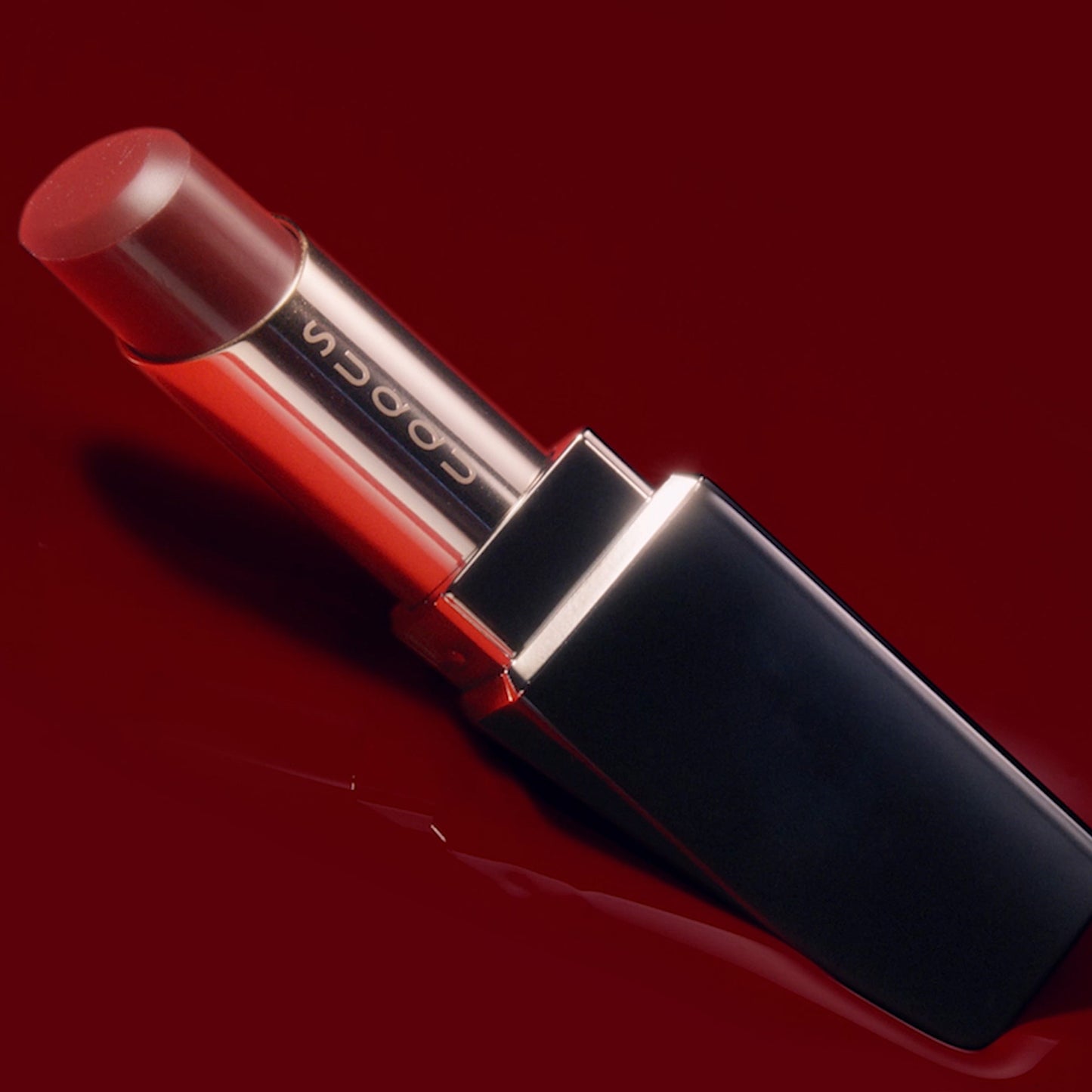 Red SUQQU Moisture Glaze Lipstick with red liquid colour background.
