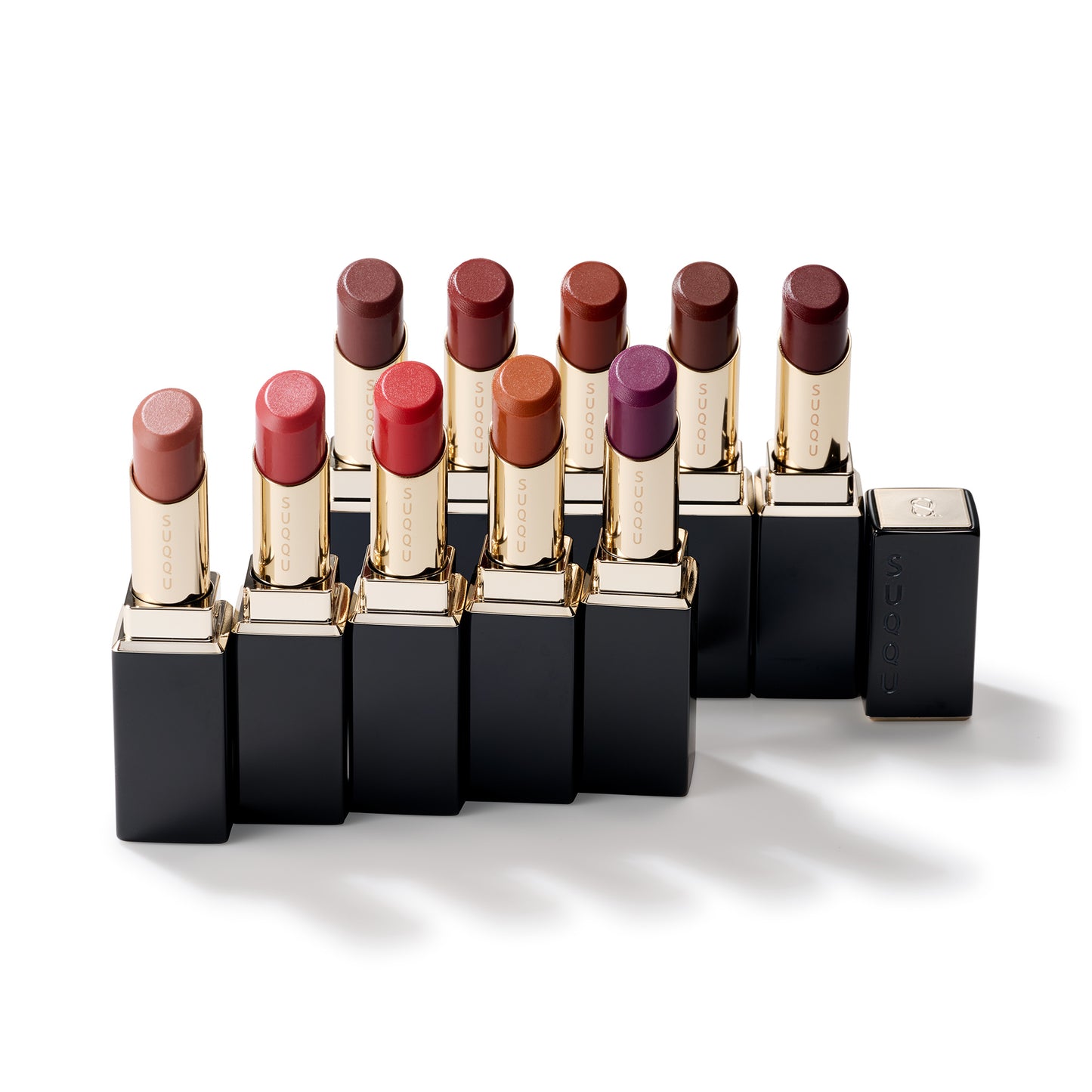 10 colourful shades of SUQQU Moisture Glaze Lipsticks with cases on a table.