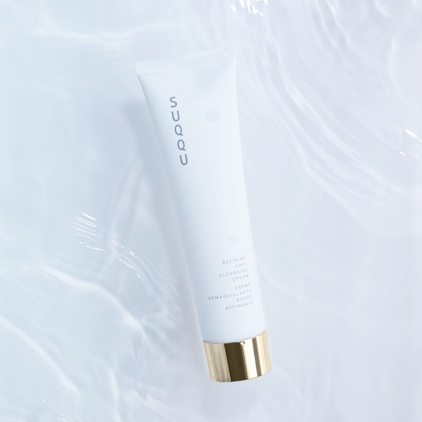 SUQQU Refining Soft Cleansing Cream luxury Japanese face cleansing skincare product tube on water ripple background.
