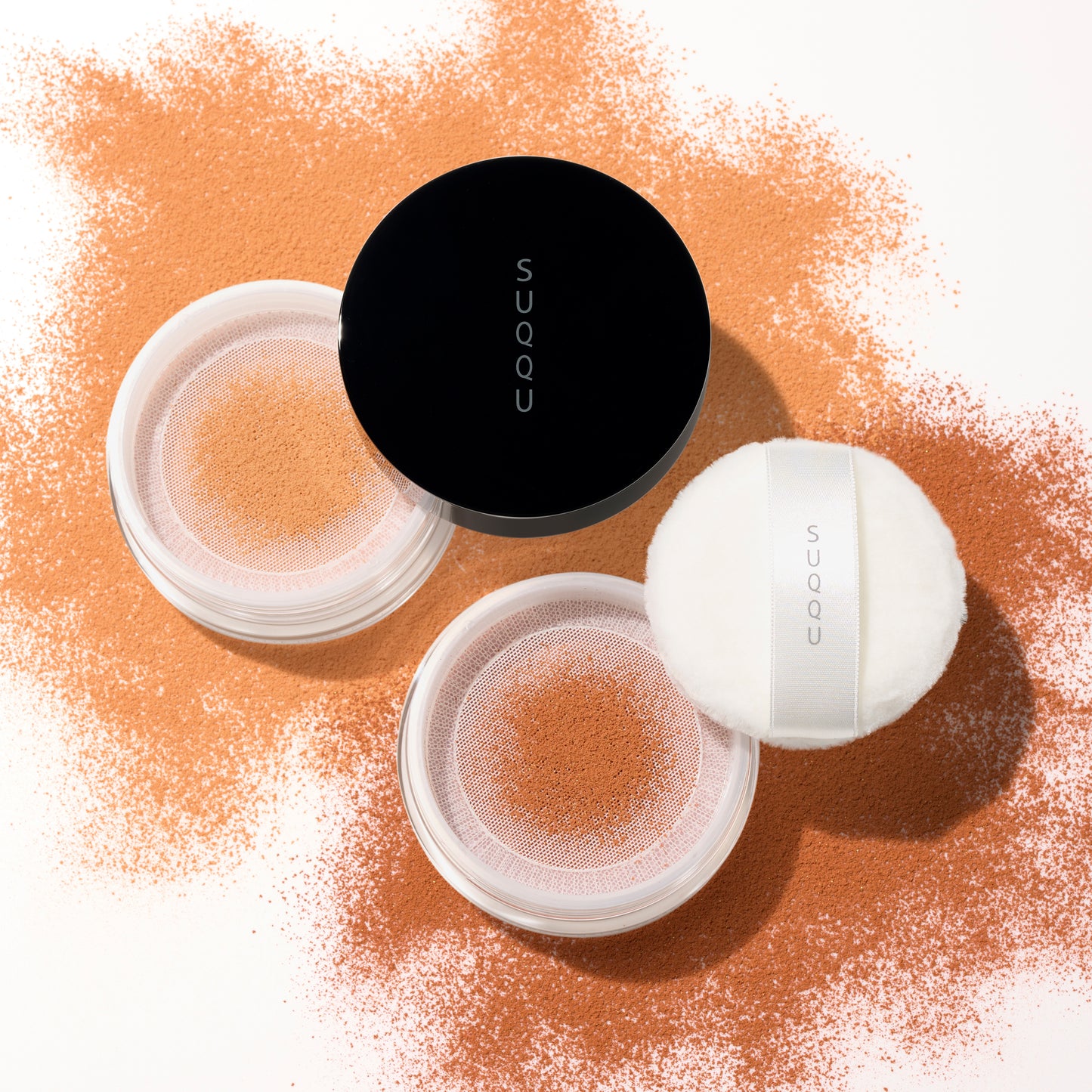 SUQQU Smooth Matte Loose Powder e30 and e40 face powder for darker skin tones on colourful powder texture background.