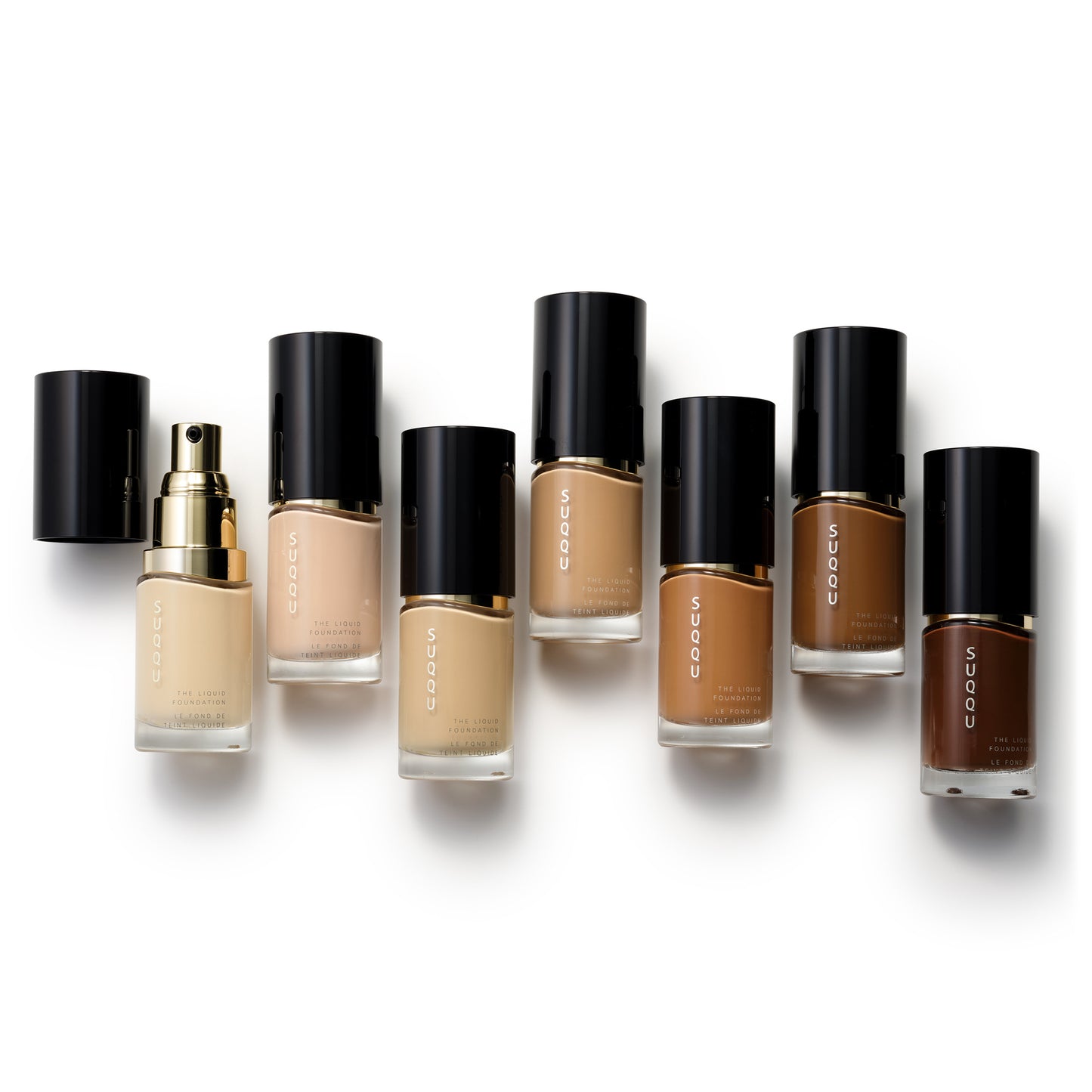 Seven selected shades of SUQQU The Liquid Foundation professional Japanese base make up bottles on plain background.