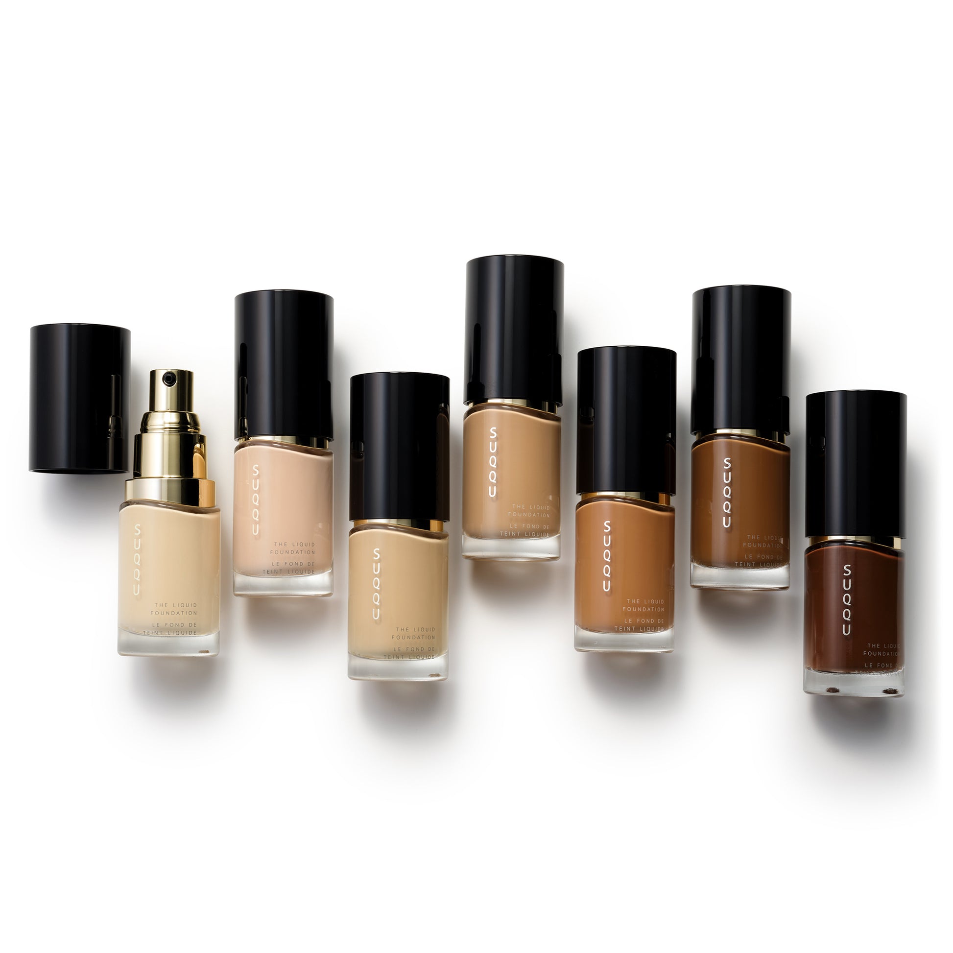 Seven selected shades of SUQQU The Liquid Foundation professional Japanese base make up bottles on plain background.