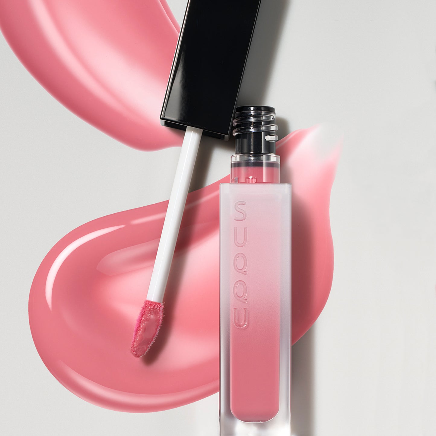 SUQQU Treatment Wrapping Lip 06 lip color gloss product and cap open with pink liquid texture background.