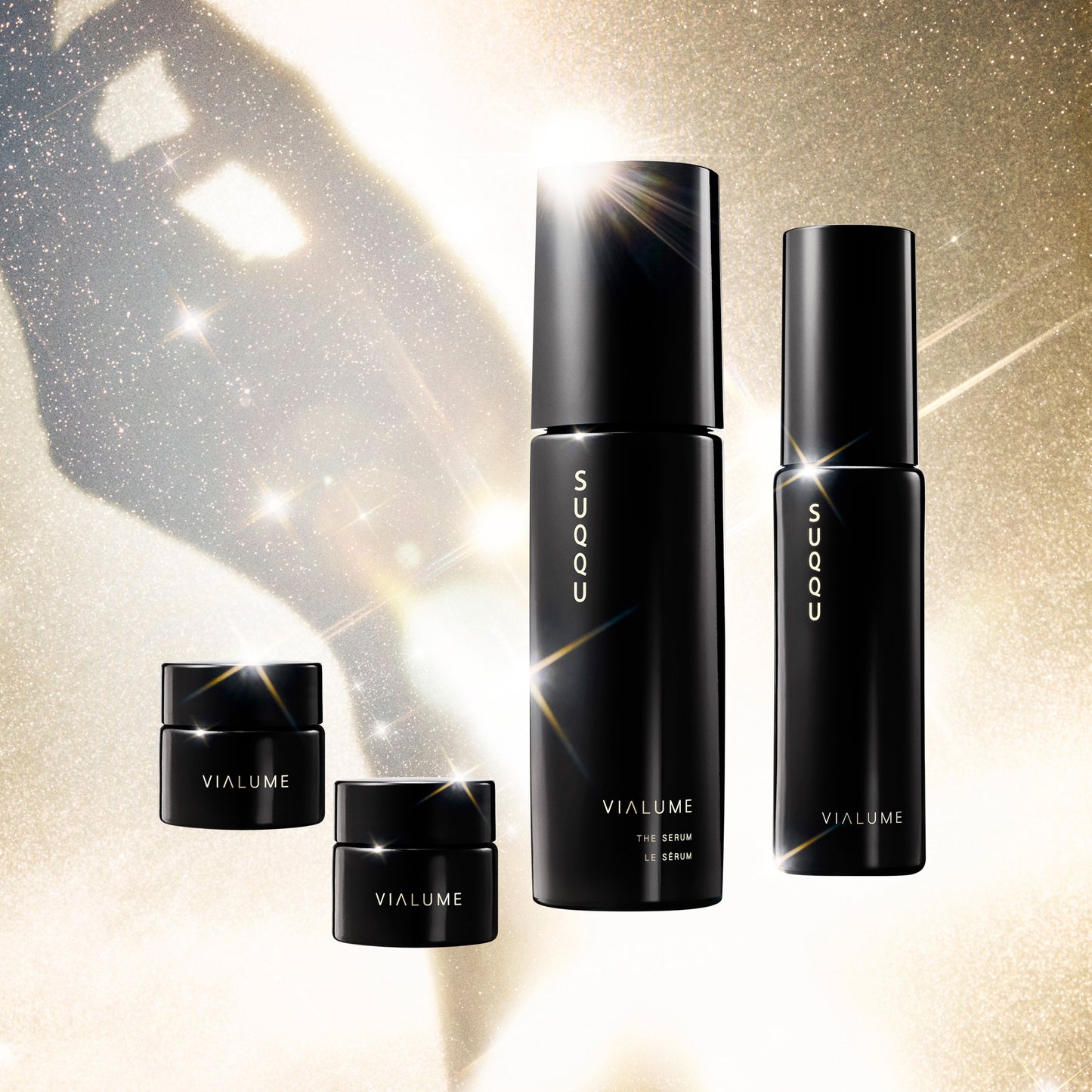 SUQQU Vialume The Kit C four luxury Japanese skincare products on a sparkling gold background. Serum, lotion, anti-ageing cream and face cream moisturisers.