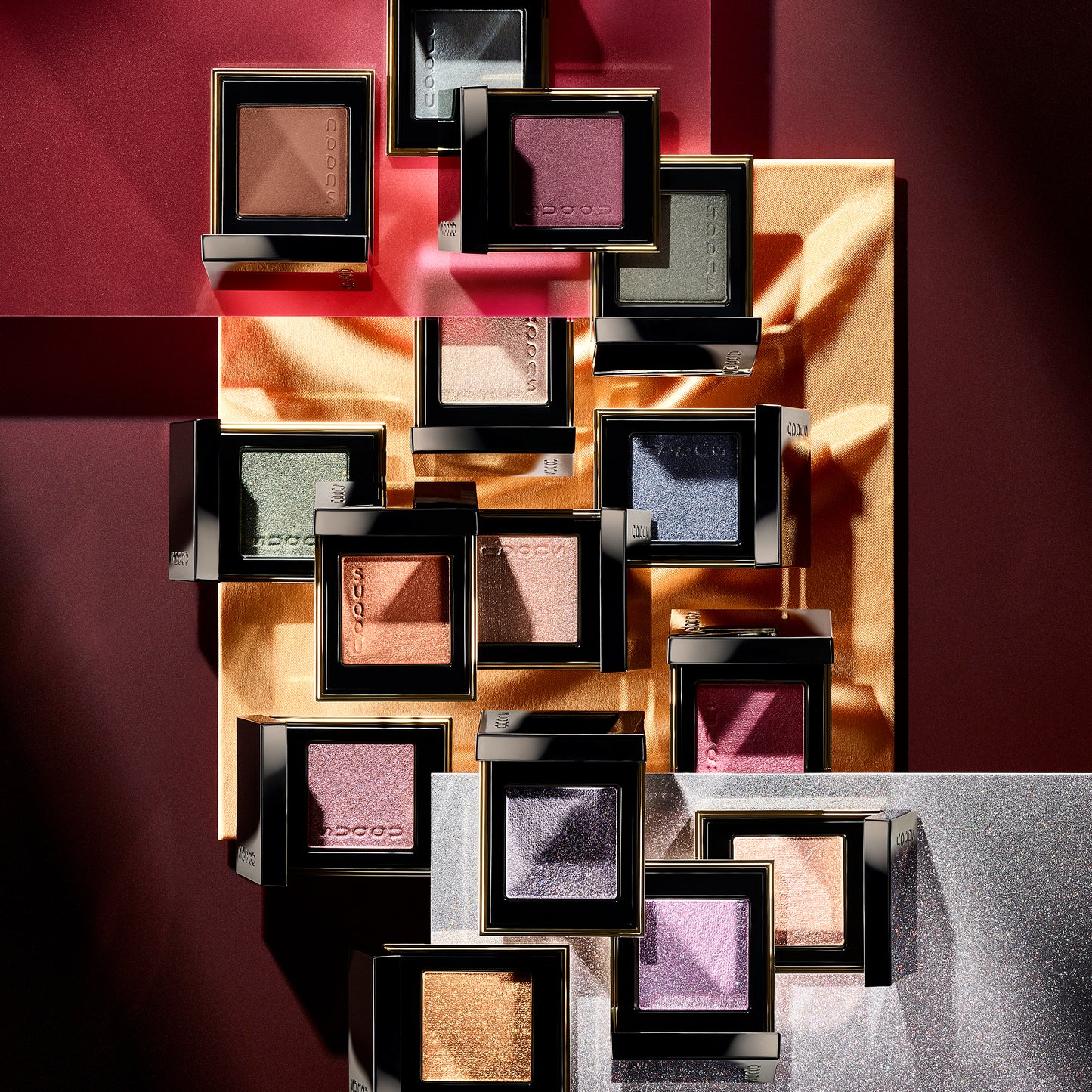 Multiple colourful SUQQU Tone Touch Eyes single eyeshadow make up palette products with lid open on multicolour background.