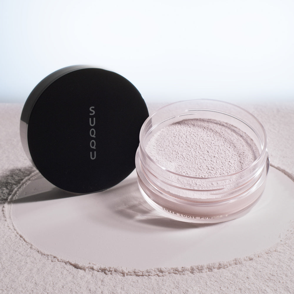 SUQQU Sheer Loose Powder e face powder pot on powdery texture background.