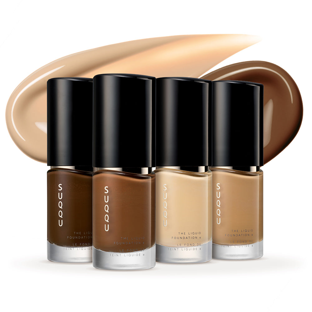 Four SUQQU The Liquid Foundation e products standing dark to light on a table with colour texture swatches in the background.