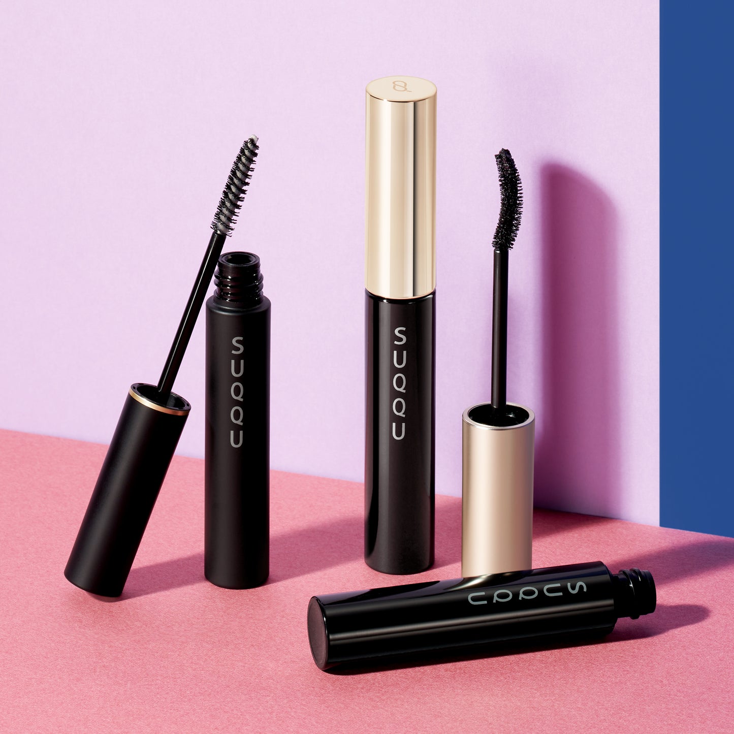Three SUQQU 3D Eyelash Mascara range of products open to show wands on multicolour background