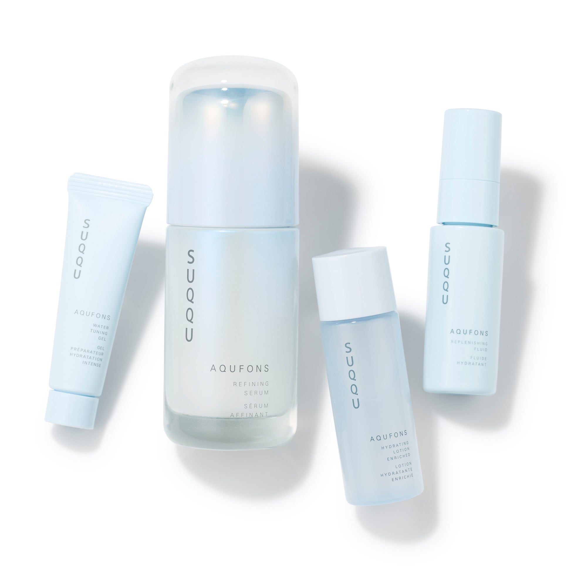 SUQQU Aqufons Refining Serum Kit four luxury Japanese skincare products on a plain background. Serum, lotion, fluid and gel moisturisers.