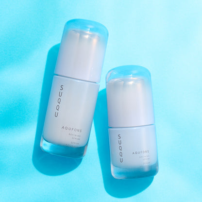 SUQQU Aqufons Refining Serum Kit luxury Japanese skincare products in two sizes on bright blue background.