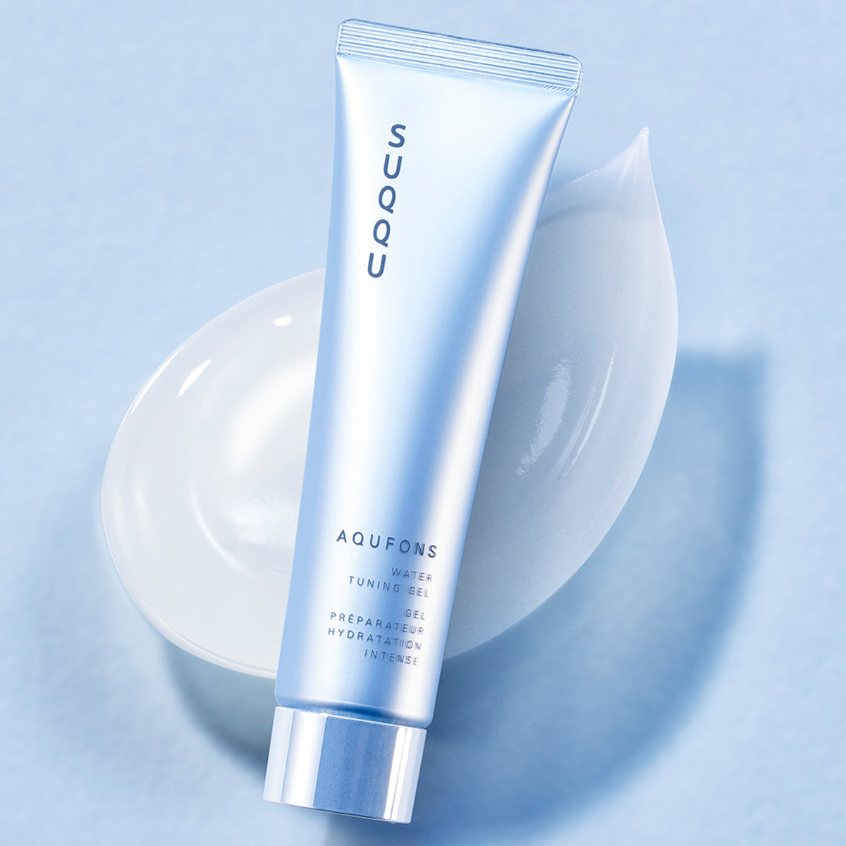 SUQQU Aqufons Water Tuning Gel skincare moisturiser tube on a blue background with gel texture swatches. Features Aqufons Complex with botanical skincare ingredients and antioxidants. Anti-gycation and autophagy face mask in a tube designed to protect collagen and keratin to improve the glow of dull looking skin, aid plumpness and promote clear translucent radiance.