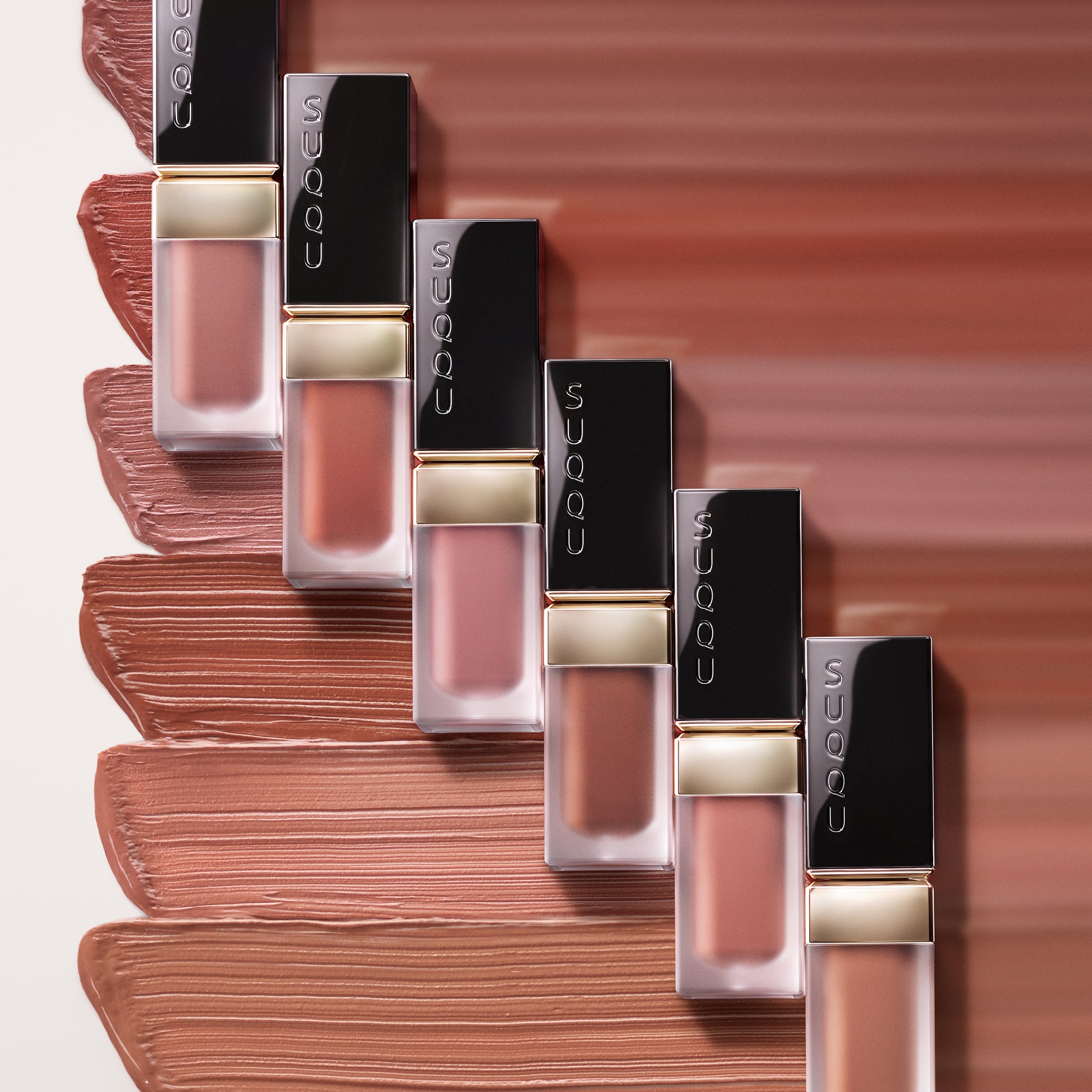 Six SUQQU Blur Liquid Lip lipsticks on blurred swatch texture background.