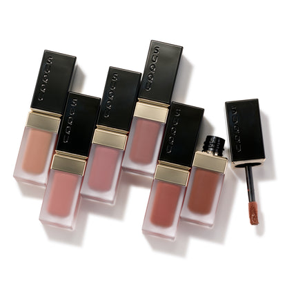 Six gorgeous SUQQU Blur Liquid Lip lipsticks on table with one product open to show applicator wand.