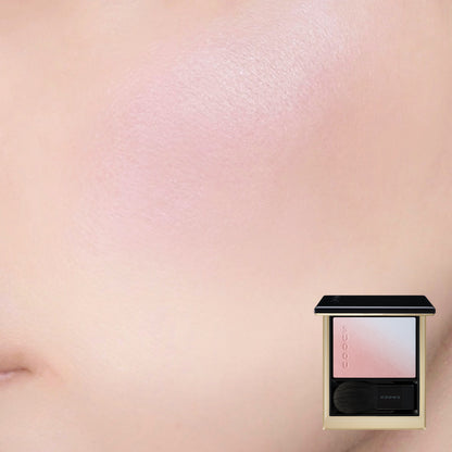 SUQQU Blurring Color Blush 118 luxury Japanese cosmetic blusher compact shown with model cheek wear close up background. Soft pink and pale blue highlighter shades.
