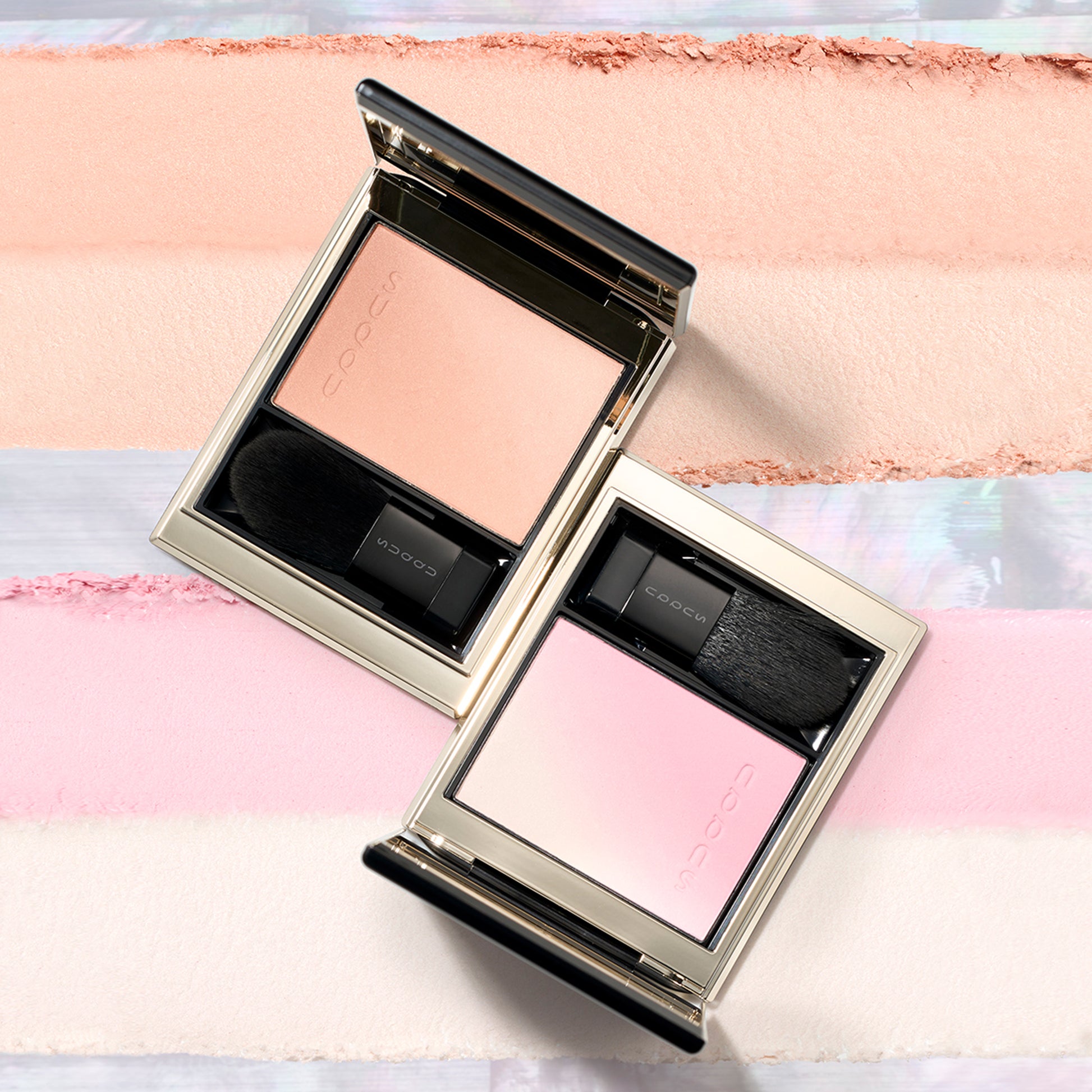 Two of the best cheek blushers from SUQQU Blurring Color Blush range. Blusher and highlighter in coral and soft beige 09 palette, also soft pink and pearl white 10 palette. Displayed on creamy skincare infused texture background colour swatch.