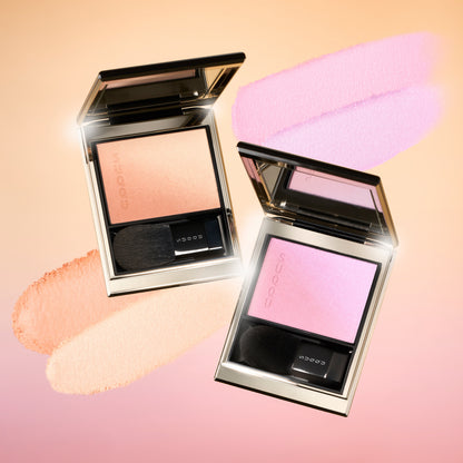 SUQQU 2026 Summer Collection, multiple beautiful colourful luxury makeup products on a gradient sky background. Two blushers with orange gold and lilac pink with texture swatches.