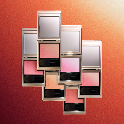 Six colourful SUQQU Blurring Color Blush palettes stacked on colourful textured gradient background.