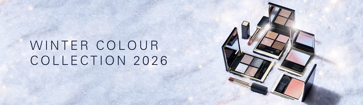 SUQQU "Winter Colour Collection 2026". A collection of beautiful winter-themed makeup products, including gorgeous eyeshadow palettes, two blushers and two red lip sticks, arranged on a snowy white background with soft light flares.