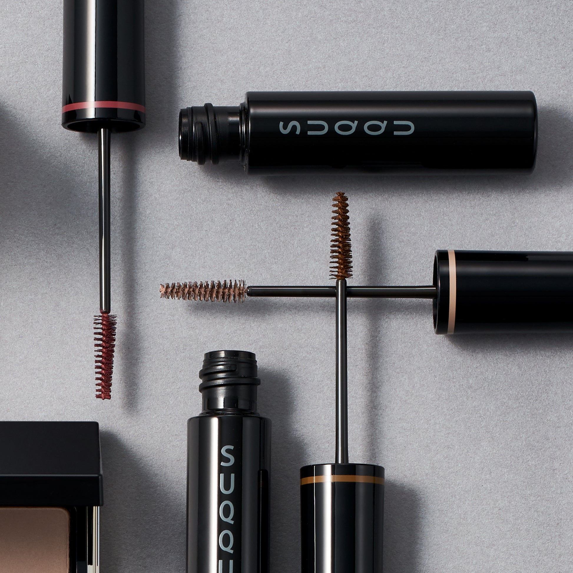SUQQU Coloring Eyebrow 01, 02 and 03 make up eyebrow mascara products overlayed on plain background showing wands.