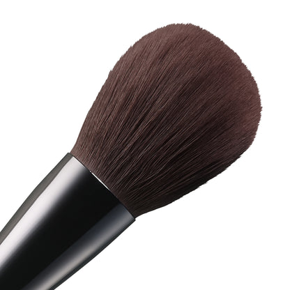 SUQQU Face Powder Brush luxury Japanese synthetic artisan professional grade make up brush for face powder bristle close up on plain background.