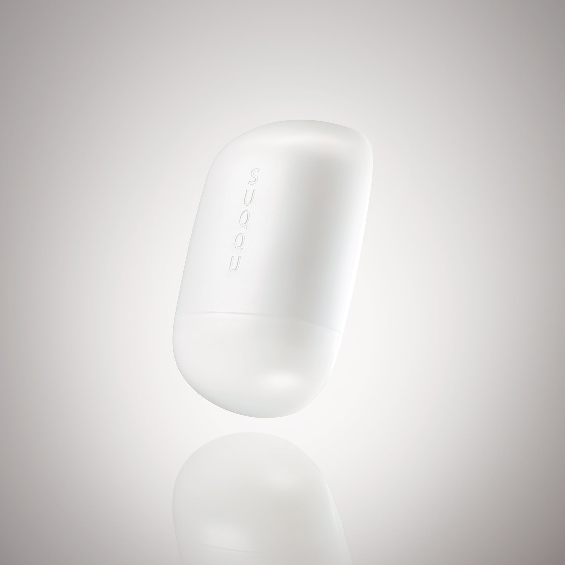 SUQQU Glowing Balm product floating on a soft grey background.