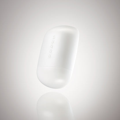 SUQQU Glowing Balm product floating on a soft grey background.