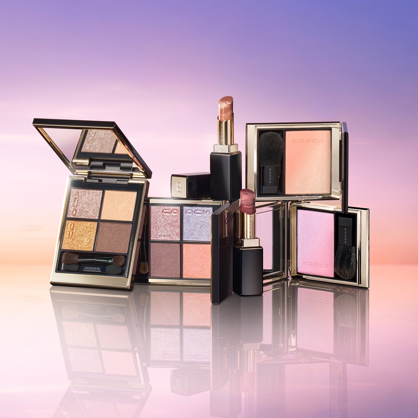 SUQQU 2026 Summer Collection, multiple beautiful colourful luxury makeup products on a gradient sky background. Two eyeshadows with gold and pink coral tones, two blushers with orange gold and lilac pink and two lipsticks in orange red and grape red.