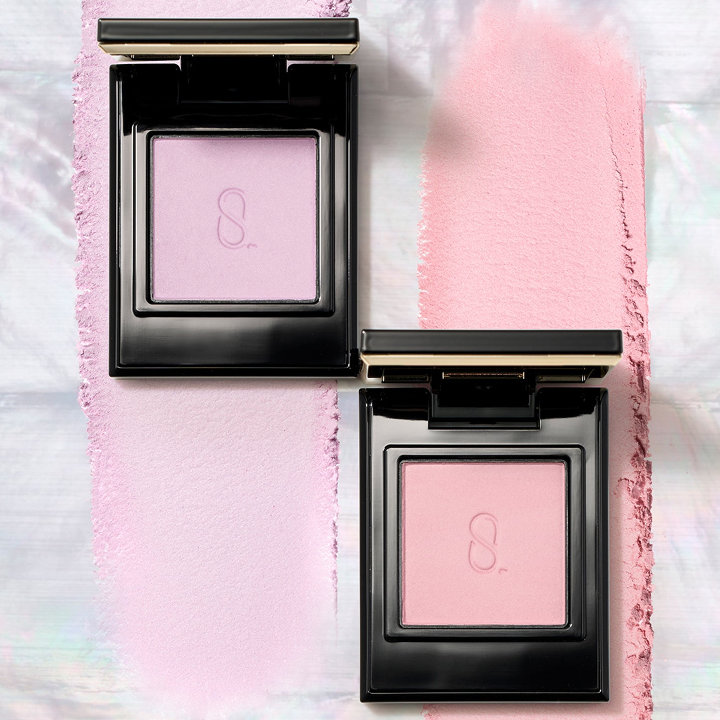 Two gorgeous SUQQU Mono Look Eyes single luxury eyeshadow palettes in pale pink M-102 and soft purple M-101 matte colours with texture swatch background.