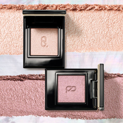 Two glittering SUQQU Mono Look Eyes single luxury eyeshadow palettes in pink gold S-102 and smoky pink purple S-103 colours with texture swatch background.
