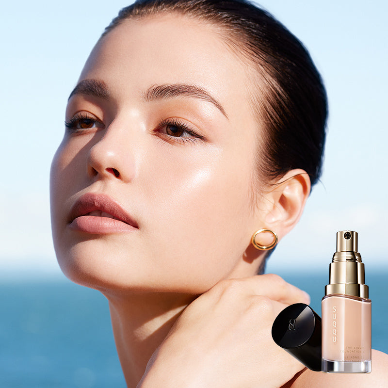 SUQQU The Liquid Foundation e model portrait wearing foundation to show the high-quality smooth and flawless skin finish. Shown with one foundation product with cap off.
