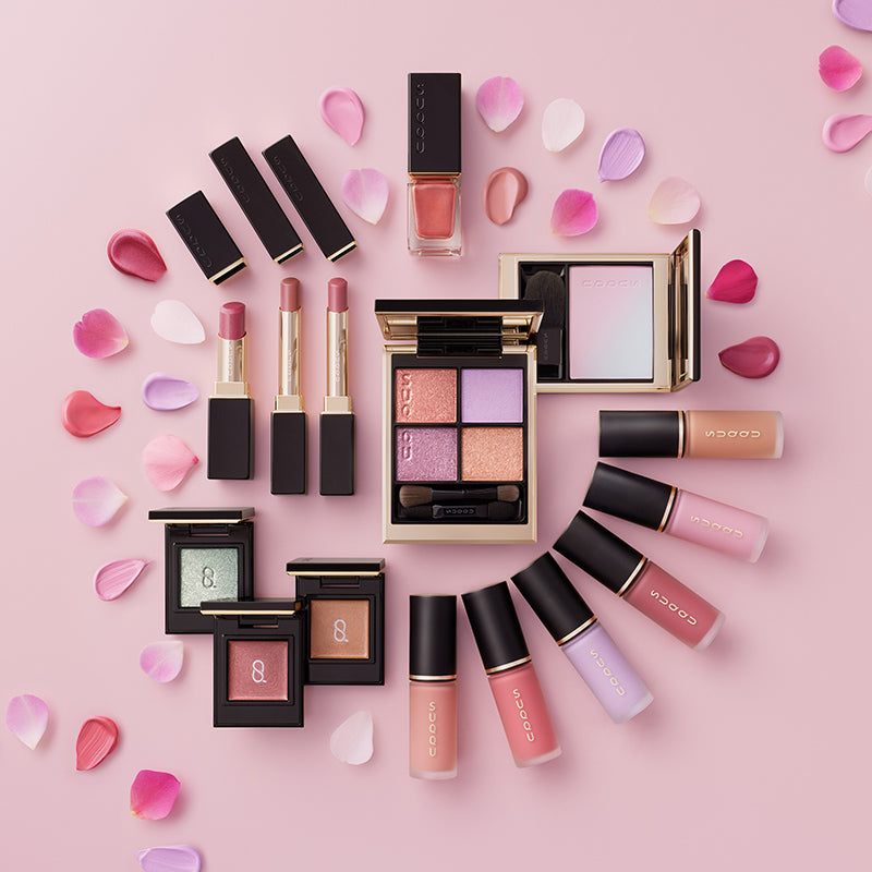 SUQQU Spring Collection 2026 group of colourful luxury makeup products lying on a table arranged in a circle with flower petals.