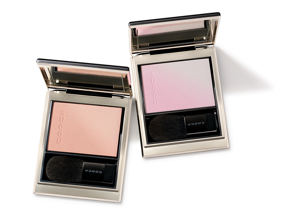 SUQQU Blurring Color Blush two gorgeous cheek blusher palettes open on table. Pearl toned pale pink with highlighter and coral with highlighter.