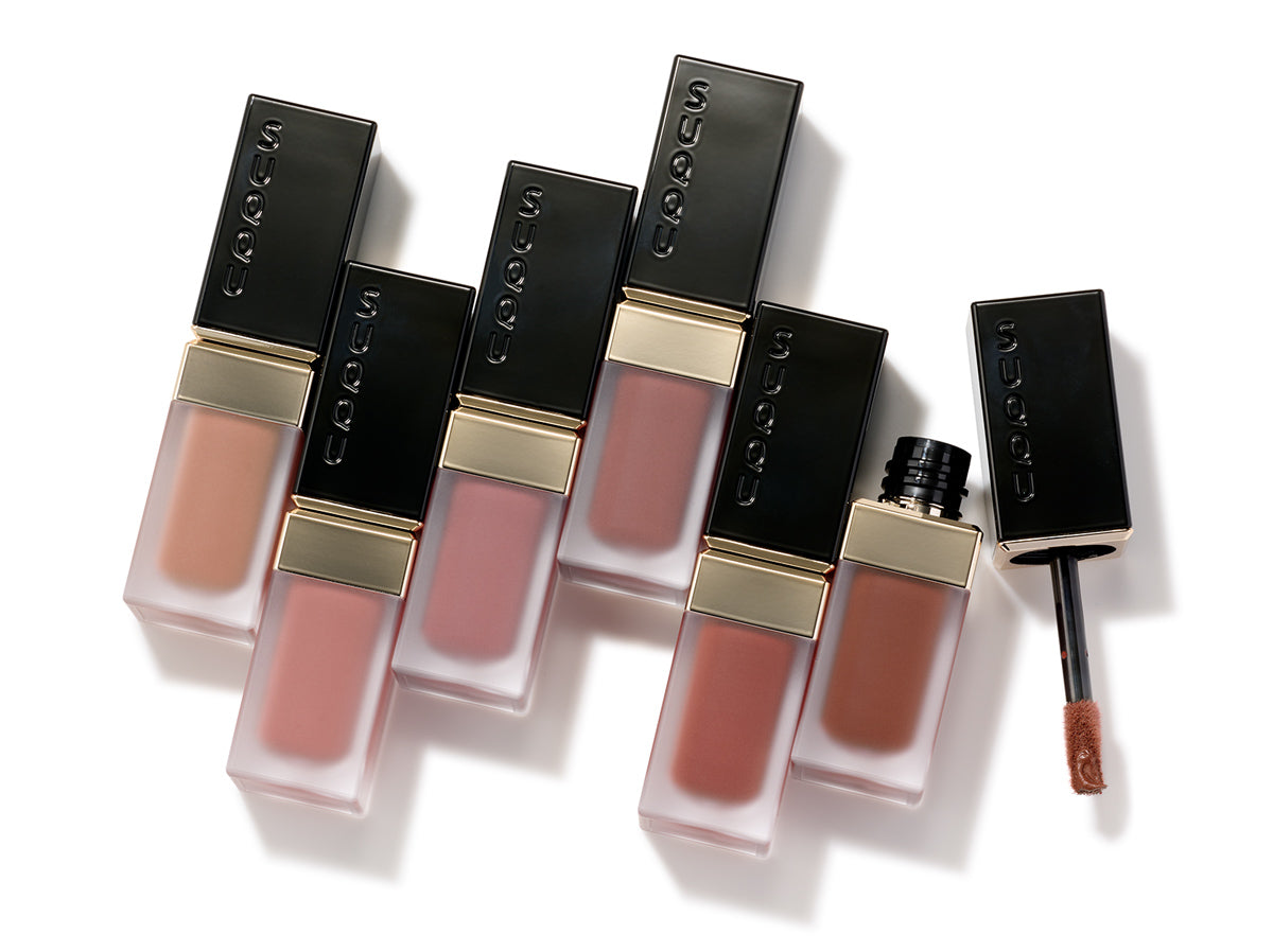 SUQQU Blur Liquid Lip. Six lipstick products on a table with one cap open showing applicator wand.
