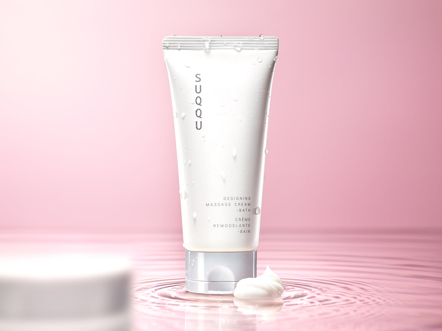 SUQQU Designing Massage Cream - Bath skincare product tube with water puddle and cream texture.