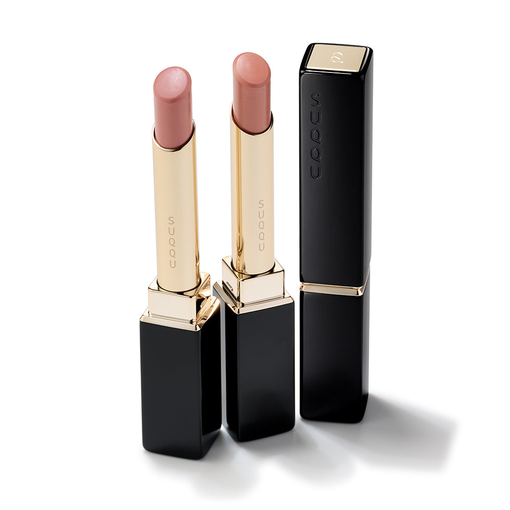 SUQQU Spring Collection 2026 group of two colourful Velvet Fit Lipstick makeup products standing open on a table next to one case with lid closed.