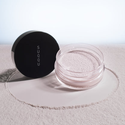 SUQQU Sheer Loose Powder e face powder pot on powdery texture background.