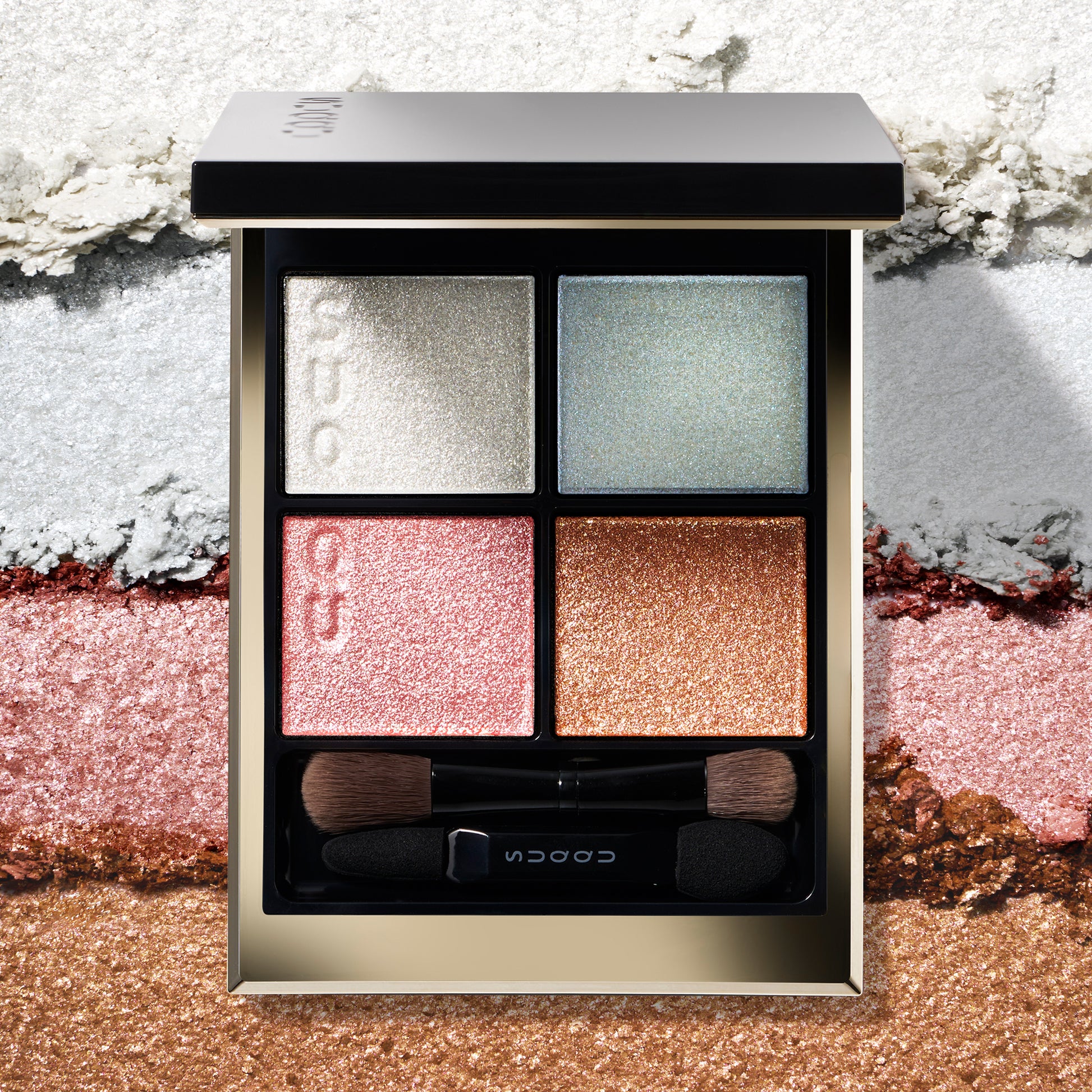 SUQQU Signature Color Eyes 156 gorgeous quad eyeshadow palette on creamy texture colour swatch background. Pale pink, blue and gold shades with shimmering pearl white highlighter.