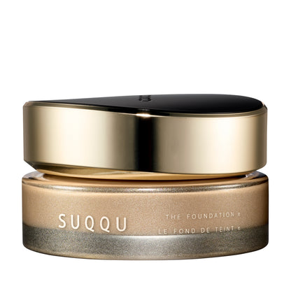SUQQU The Foundation e 025 luxury cream base makeup jar on plain white background with gold and black lid and frosted glass base. Light to Medium beige cream foundation shade.