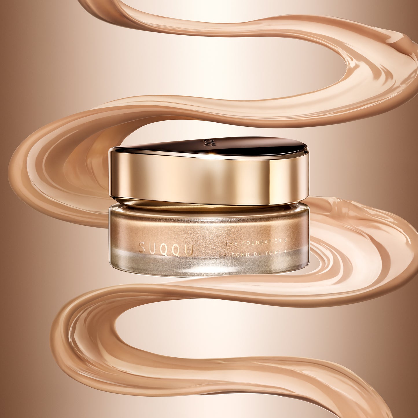SUQQU 'The Foundation e' jar with a black lid and metallic rose-gold base, surrounded by flowing beige foundation swirled with a cream background. The best cream foundation from base make up experts SUQQU.