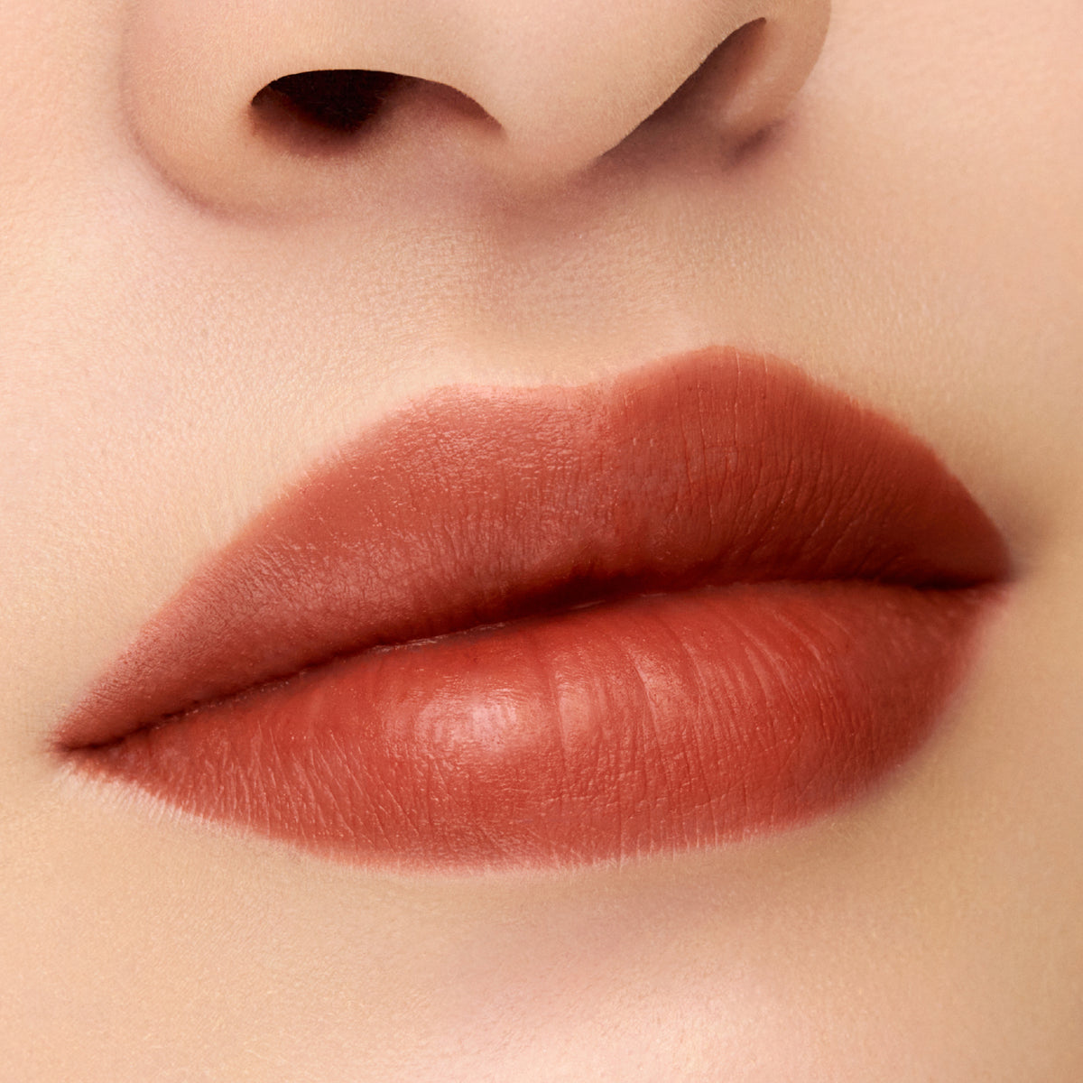 SUQQU Velvet Fit Lipstick close-up of a person's lips wearing a matte, warm red-brown lipstick.