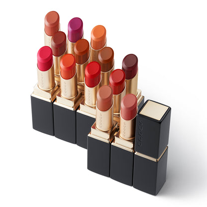Various SUQQU Vibrant Rich Lipsticks shades with caps open and case on table.
