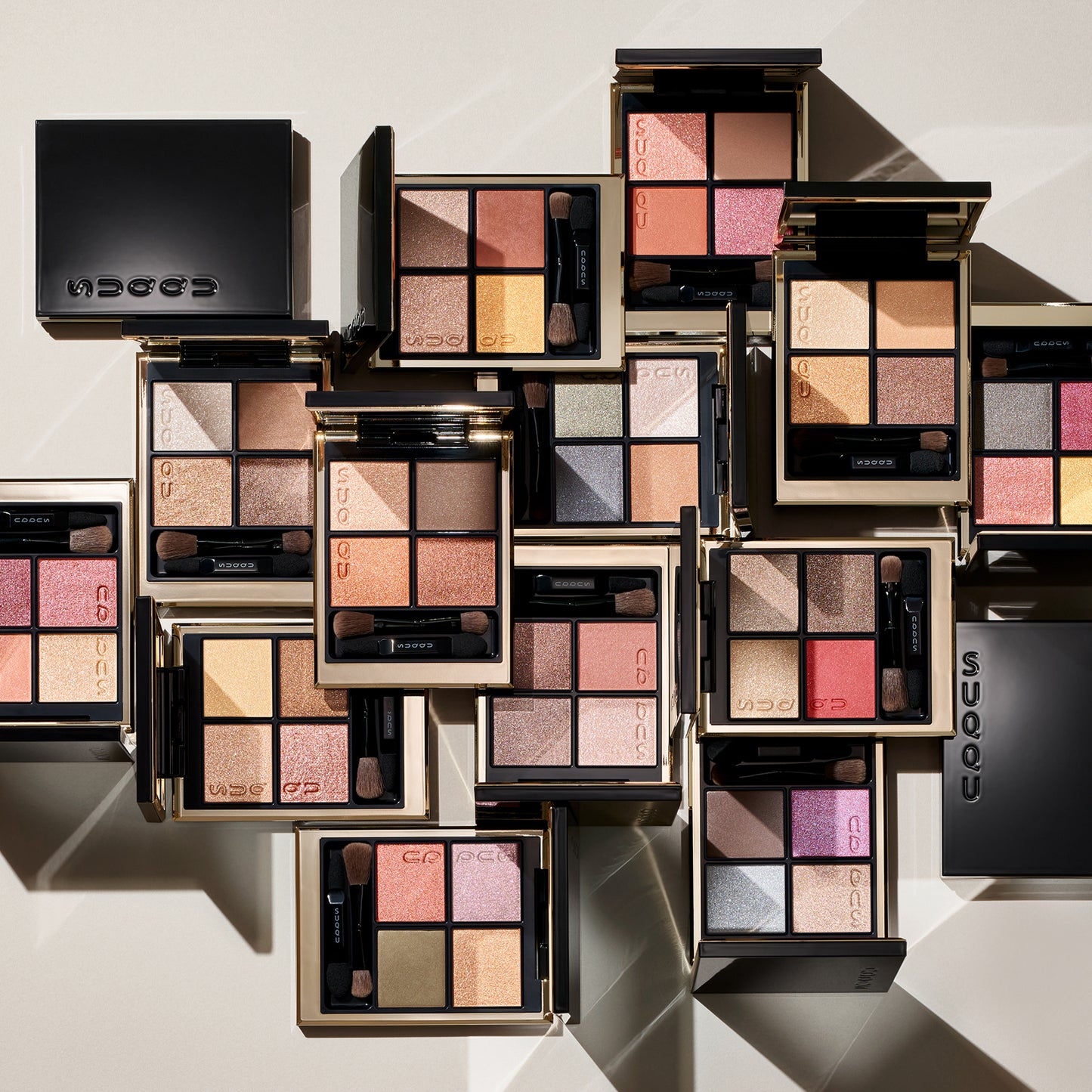 Multiple colourful SUQQU Signature Color Eyes eyeshadow palettes arranged on a table.