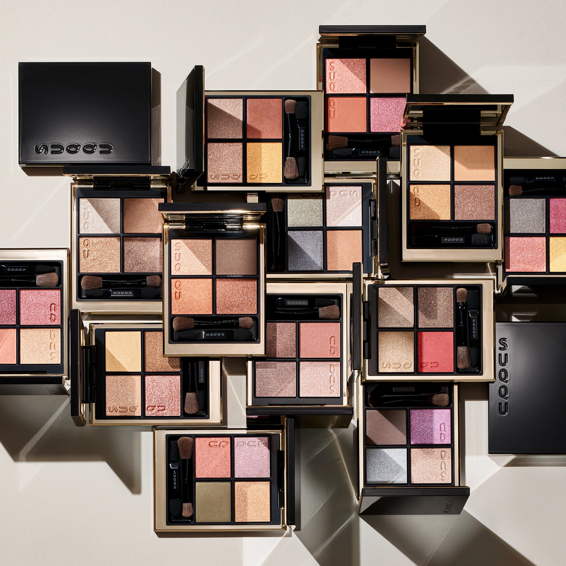 Multiple colourful SUQQU Signature Color Eyes eyeshadow palettes arranged on a table.