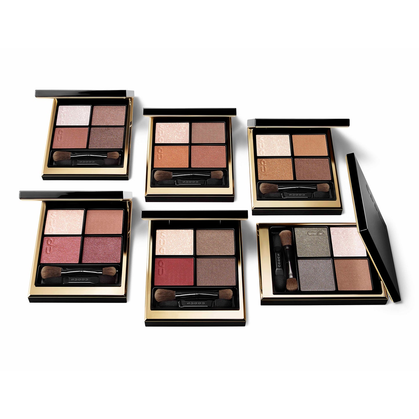 Group of six SUQQU Signature Color Eyes eyeshadow quad colour make up palettes open on plain background.